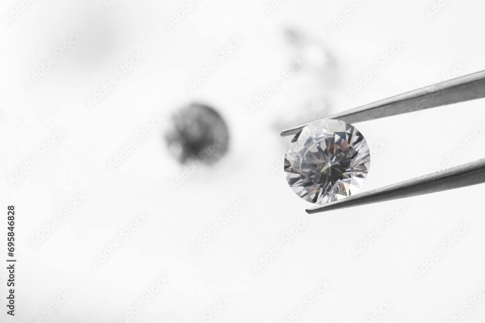 Wall mural tweezers with beautiful shiny diamond on light background, closeup. space for text