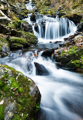 Blurred waterfall throughing mossy rocks