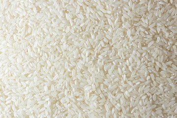 Dry Uncooked White Rice Background - Top View, Flat Lay. Scattered Raw Long Grain Rice. Asian Cuisine and Culture. Healthy Eating Ingredients. Diet Food