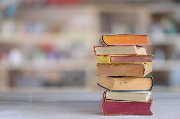 Stack of books with blurred bookshelf background, reading, learning, education or home office...