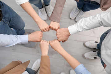 People holding fists together indoors, top view