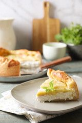 Piece of freshly baked rhubarb pie with cream cheese and mint leaves on grey wooden table