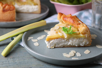 Freshly baked rhubarb pie with cream cheese, stalks and almond flakes on grey wooden table, closeup
