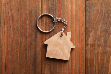 One keychain in shape of house on wooden table, top view