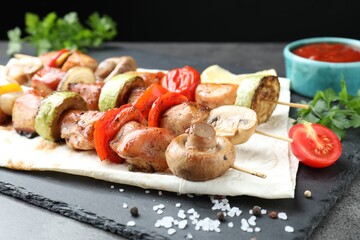 Delicious shish kebabs with mushroom, onion, tomato and zucchini on grey table, closeup