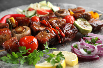 Delicious shish kebabs with vegetables on table, closeup