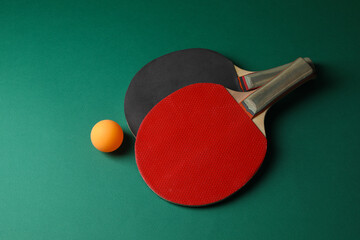 Ping pong ball and rackets on green background, flat lay