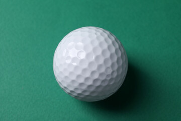 One golf ball on green background, top view