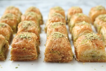 Delicious fresh baklava with chopped nuts on white table, closeup. Eastern sweets