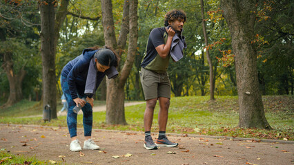 Indian Arabian couple jogging outdoors run together woman man in park stop pause break tired...