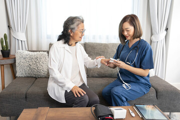 asian senior woman talking with a home visiting nurse,young female nurse measuring pulse with oximeter,concept of elderly people lifestyle,homecare,home health nursing