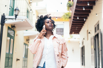 Stylish black woman walking on the city street talking on the phone