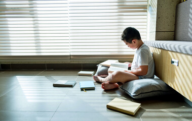 Little boy sitting on floor and reading a book