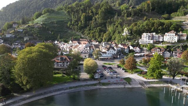 Aerial footage of a city in the valley around the lush green mountains on the bank of the lake 