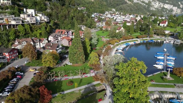 Aerial shot of a city in the hilly area situated in the valley with lakes containing motor sports vehicles and a fountain 
