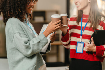 African American trainee with an afro and a Caucasian colleague in an office, both looking at a tablet and smiling.