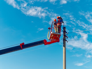 Two electricians from cradle of aerial platform or crane are repairing street lighting lamp....