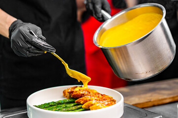 Professional chef cooking Baked fresh asparagus with wrapped meat in restaurant kitchen