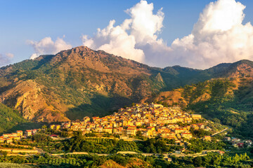 highland landscape of italian town between amazing green mountains with scenic sunset cloudy sky on background