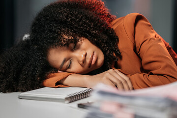 Exhausted woman sleeping on his office desk, next to laptop and documents, tired of overworking....