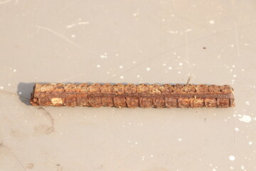 A small piece of rusted iron rod or sariya on cemented floor under sunlight, horizontal