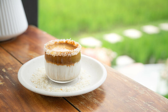 glass of ice latte with coconut milk on wooden table in copy space concept.