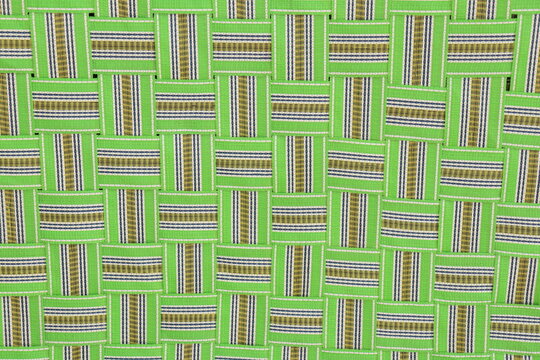 Green colored nylon Foldable Khatia or chaarpai standing with support of white wall , closeup of criss cross pattern