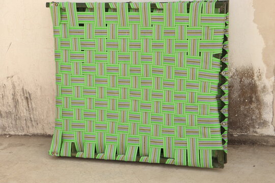 Green colored nylon Foldable Khatia or chaarpai standing with support of white wall 