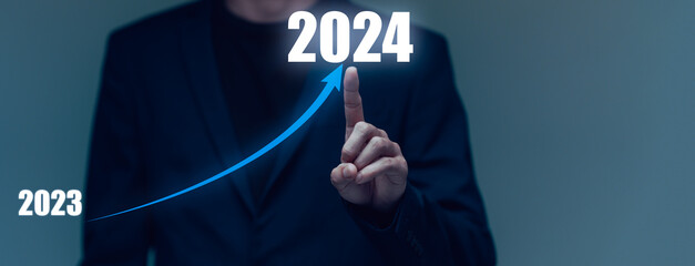 Businessman hand drawing line for increasing arrow from 2023 to 2024 for preparation happy new year...