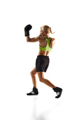 Full-length image of young woman with muscular fir body training, practicing punches isolated over white background. Concept of sport, active and healthy lifestyle, strength and endurance, body care