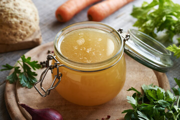 A jar of chicken bone broth or soup with fresh vegetables - obrazy, fototapety, plakaty