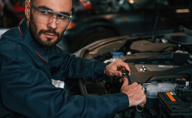 Hood is opened, fixing. Car repairman is in the garage with automobile