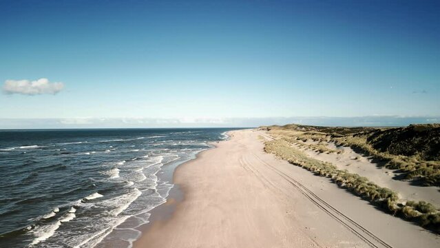 Drone footage of on a sandy beach under blue sky on a sunny day
