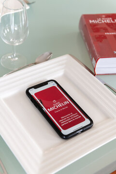 Paris, France - December 20, 2023 - Red Michelin guide book and smartphone application, which reviews restaurants.