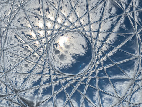upward view of the sky with sun shining through clouds seen through a beveled or cut glass window