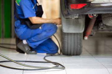 Auto mechanic checking air pressure and inflating car tires after changing new tire. Focus on air...