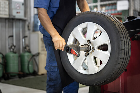 Auto mechanic uses tire balancing machine and turning tire. Computer wheel alignment. Balancing tire wheel machine. Tyre assembling. Tyre balancing of modern car in workshop.