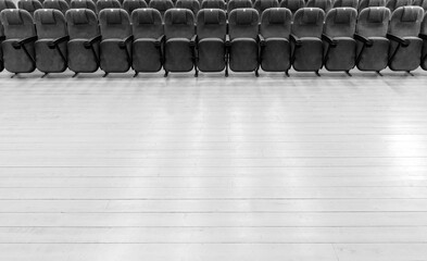 a large wooden platform in front of rows of chairs in the auditorium of a rural cinema or theater black and white photo