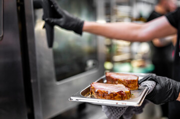 chef hand cooking pork meat in oven on kitchen