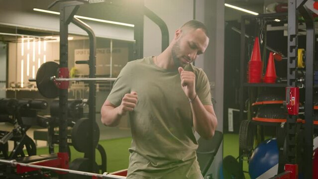 Funny happy carefree silly American Latino ethnic man athlete fit sport guy personal fitness trainer instructor male in gym bodybuilder sportsman dancing having fun moving listening music dance active