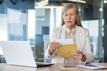 Businesswoman boss received letter mail notification message with bad news, upset and sad senior woman reading news data , female worker inside office at workplace.