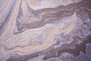 A marble texture of a rainbow spill of gasoline on a sidewalk in a puddle as a background.