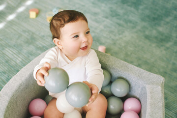 Adorable baby girl playing with mini ball pit, fun and activities for little kids - 695934486