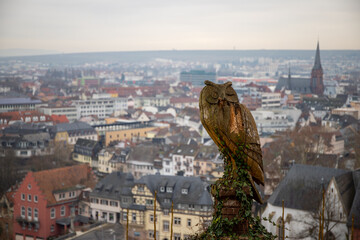 an owl carved out of wood with a city in the background