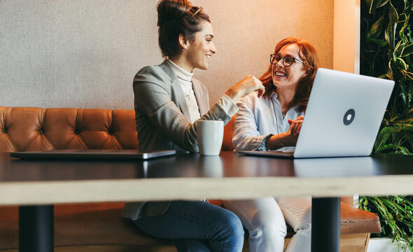 Female colleagues discussing software design in a coworking office