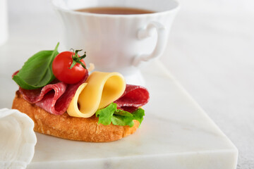 Salami sandwich. Delicious toasted sandwiches with slice salami, cheddar cheese lettuce and tomatoes cherry on white marble background. Restaurant menu, cafe, recipe or article concept. Mock up.