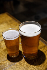 Half pint and pint of lager beer in a wooden table in a pub or bar