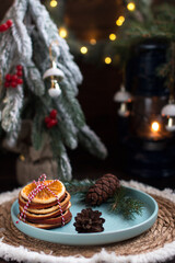 A Christmas tree with toys and a plate with red viburnum berries and orange slices. New Year's lights