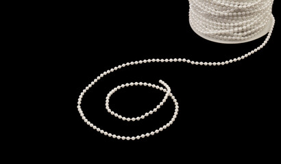 White beads on a string on a black background