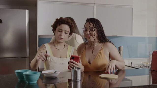 Women in the kitchen using a smartphone to check the items in a recipe. Cinematic 4k.